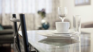 A dining table with white plates, a cup, and a glass. - Enjoyable 2-bedroom apartment with AC in Miraflores neighborhood (Miraflores)
