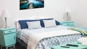 A bed with a patterned bedspread, two bedside tables with lamps, a clock, and a remote control on a chest of drawers. - Enjoyable 2-bedroom apartment with AC in Miraflores neighborhood (Miraflores)