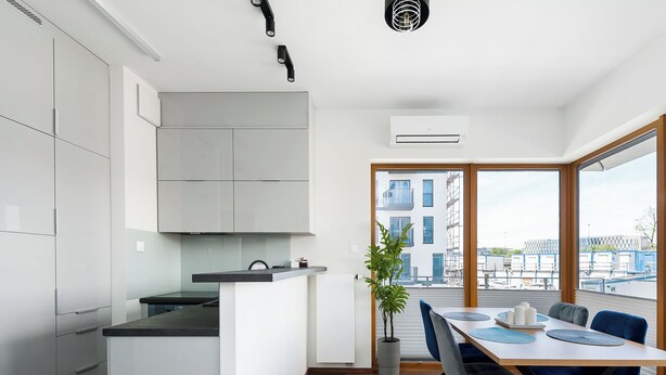 Una cocina moderna con armarios blancos, una isla central y un comedor con mesa y sillas.