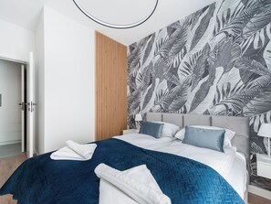 A modern bedroom with a bed, a wooden panel wall, and a tropical leaf pattern wallpaper. - Apartment Novum by Interhome (Krakow)