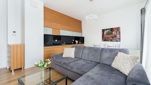 Una sala moderna con un sofá seccional gris, una mesa de centro de vidrio y un mueble de madera.