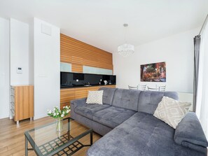 A modern living room with a grey sectional sofa, a glass coffee table, and a wooden cabinet. - Apartment Novum by Interhome (Krakow)