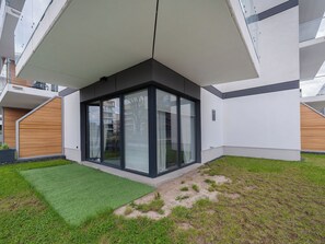 A modern building with a corner entrance, large glass doors, and a small grassy area in front. - Apartment Novum by Interhome (Krakow)