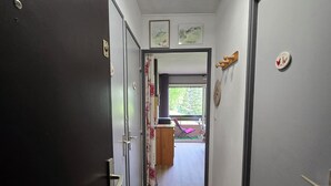 A hallway with a wooden floor, a ceiling light fixture, and a door on the left. - South-facing mountain apartment: summer/winter ideal for biking, climbing, hiking and skiing (Briançon)