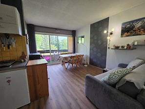 Un espacio habitable pequeño con kitchenette, comedor y sofá.