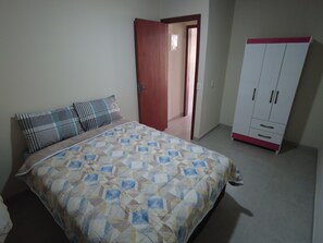 Une chambre à coucher comprenant un lit, une armoire et une porte donnant sur une autre pièce.