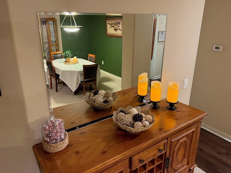 A dining area with a table set for four, a mirror reflecting the room, and a wooden cabinet with decorative items.. Rest & Relax Cozy Western Luxe Stay