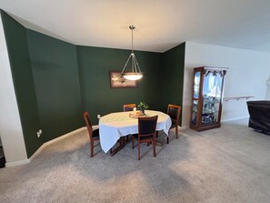 A dining area with a round table, chairs, a chandelier, and a glass cabinet.