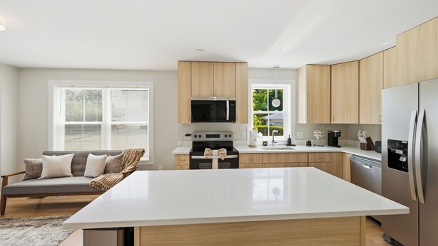 A modern kitchen with a large island, built-in appliances, and a cozy seating area.