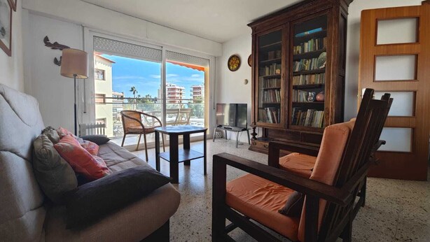 Ein Wohnzimmer mit einer Couch, einem Sessel und einer Holzkommode mit Büchern.