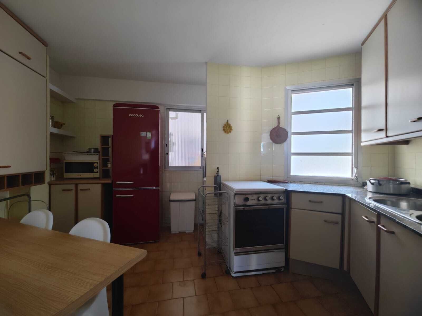 Une cuisine de taille réduite, équipée d’un réfrigérateur, d’une cuisinière et d’une fenêtre.