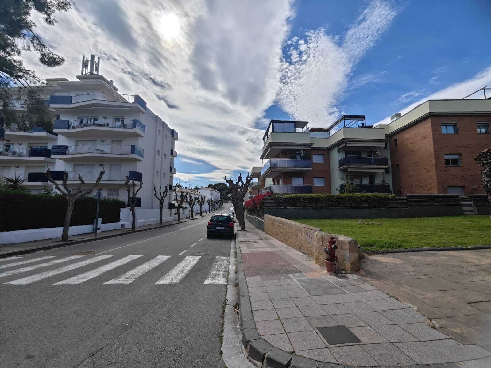 En boligvej med moderne lejlighedskomplekser, et fodgængerfelt og en brandhane.