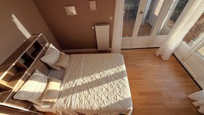 Un dormitorio con cama, mesita de noche y vistas a través de un ventanal corredero.