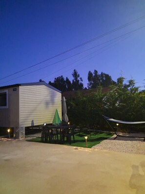 A single-story building with a patio area, outdoor seating, and a hammock.