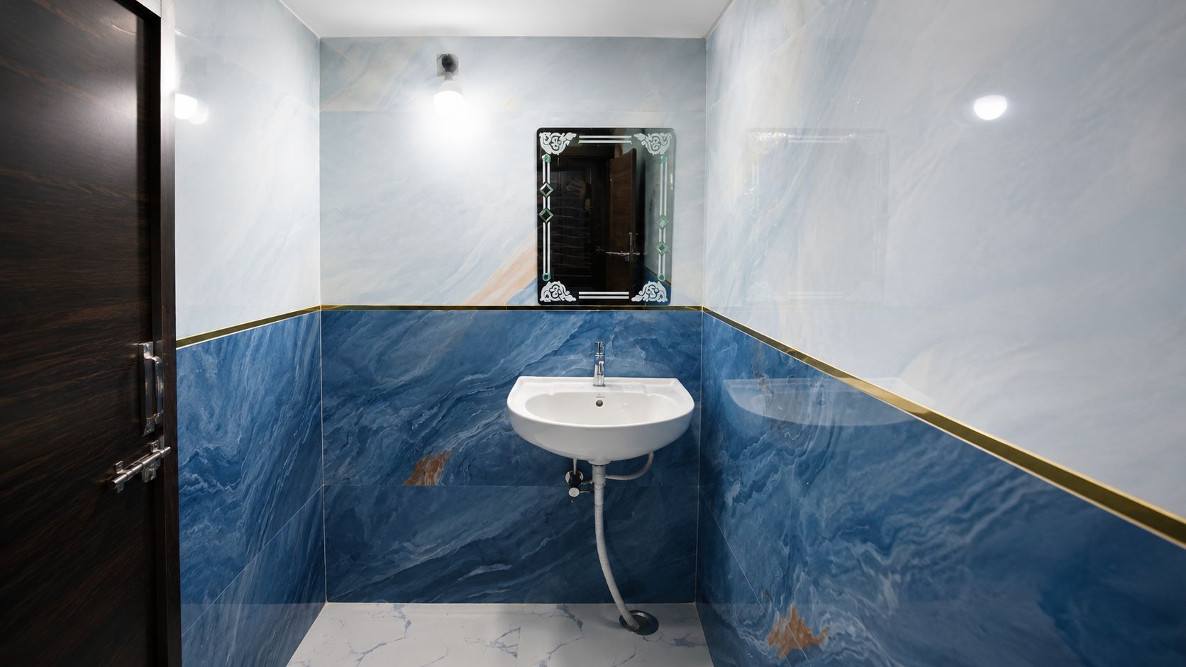 A bathroom with a marble wall, a sink, and a mirror.