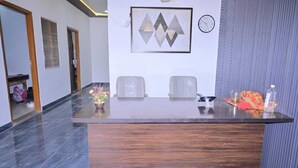 A reception desk with two chairs, a clock, and a framed artwork on the wall. - Monishka Palace  (Faizabad)