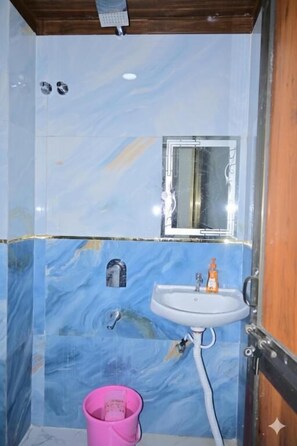 A bathroom with a sink, mirror, and pink bucket. - Monishka Palace  (Faizabad)