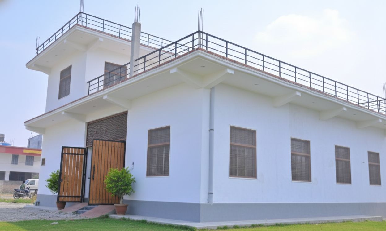 A two-story building with a flat roof, a gated entrance, and a small garden area.