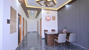 A conference room with a long table, two chairs, a ceiling fan, and a clock on the wall. - Monishka Palace  (Faizabad)