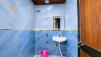 Un baño con pared de mármol, lavamanos, espejo y puerta de madera.