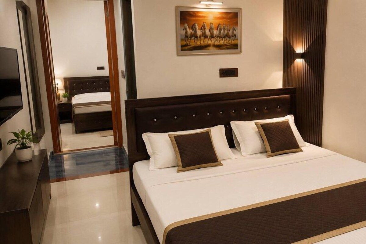 A hotel room with a large bed, a television, a painting on the wall, and a wooden headboard.