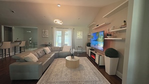 Uma sala de estar moderna com um sofá modular, uma televisão de tela plana, uma mesa de centro e um tapete estampado.