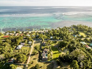 Ein Luftbild eines Küstenresorts mit mehreren bungalowartigen Unterkünften, einem zentral gelegenen Pool und einem Strand.