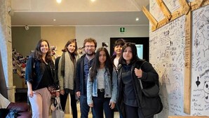 Un gruppo di persone in una stanza con una parete di legno ricoperta di scritte, un divano e un tavolo con una lampada.
