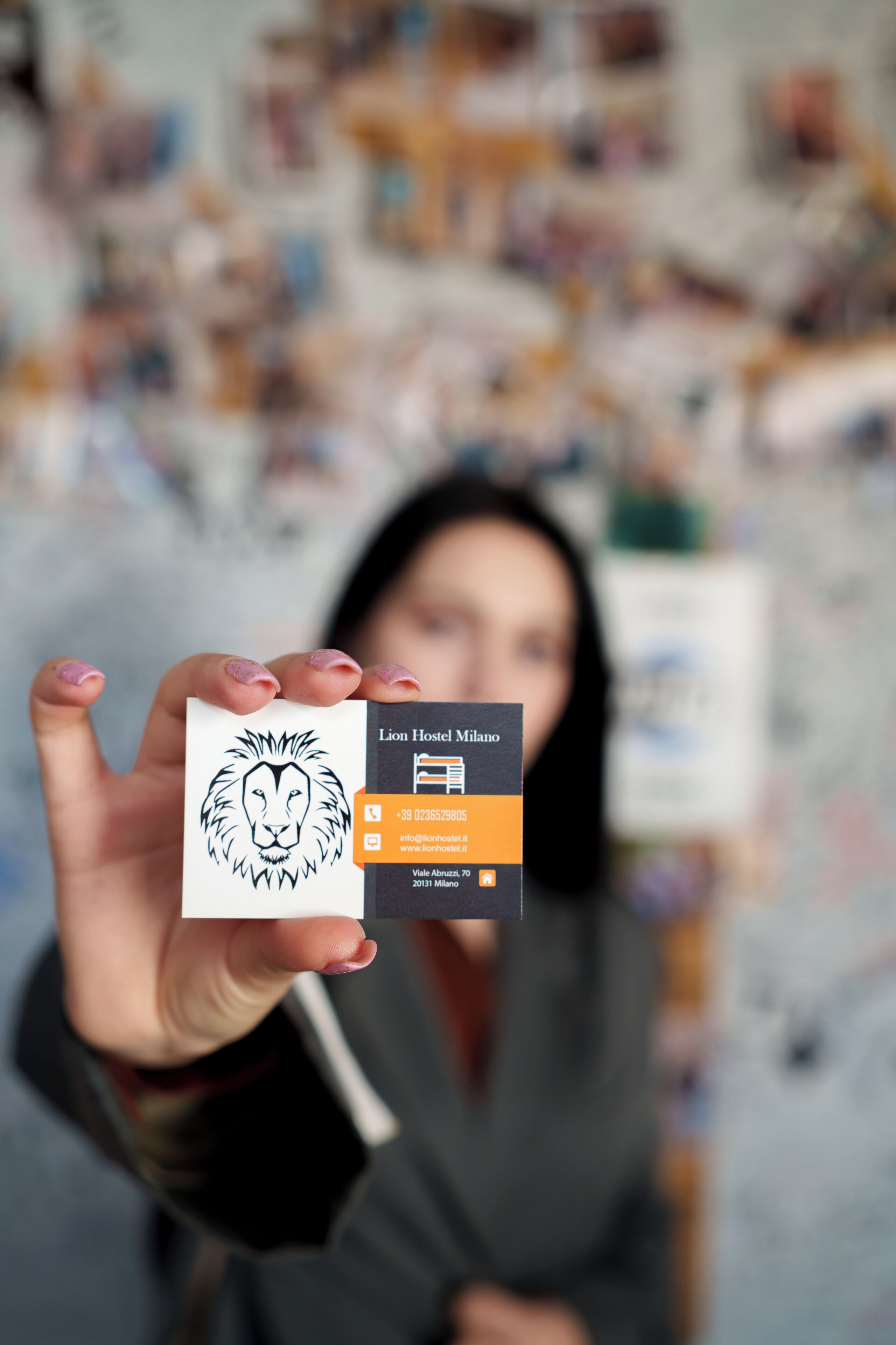 A business card with a lion logo and text for Lion Hostel Milano, including contact information and address.