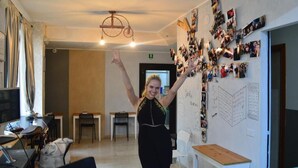 Una stanza con una lavagna ricoperta di foto e appunti, una ventola a soffitto e un orologio a parete.