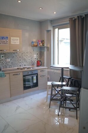A kitchen with a window, a sink, a stove, and a dining area with chairs.
