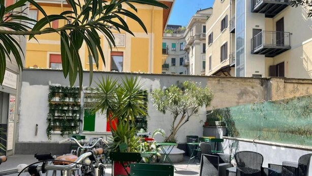 Un'area esterna con tavoli e sedie, biciclette e piante in vaso.