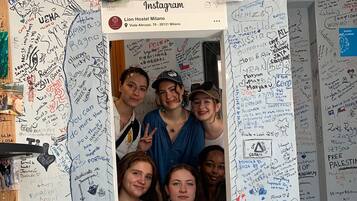 A wall with numerous handwritten messages and drawings, including a photo booth with a white frame and a social media post overlay.