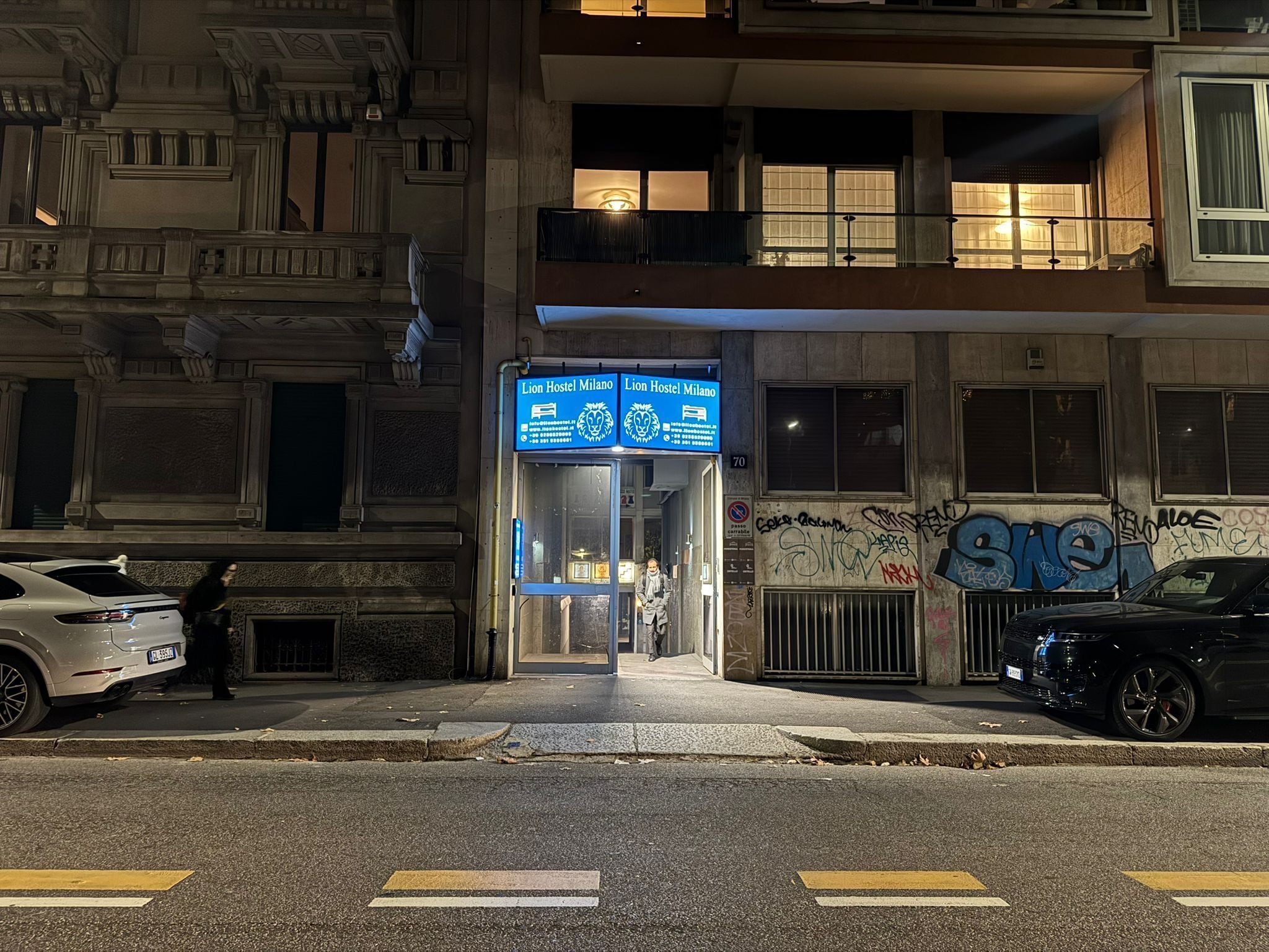 En byggnad med en skylt som visar att det är ett vandrarhem, en grind vid ingången och klotter på väggen.
