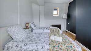 Una camera da letto con due letti, una piccola finestra, un termosifone e una lampada.