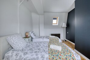 Ein Schlafzimmer mit zwei Betten, einem kleinen Fenster, einem Heizkörper und einer Lampe.