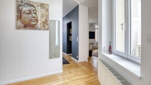 Un interno moderno con pavimento in legno, un'ampia finestra e una statua di Buddha sulla parete.