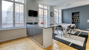 Una cucina moderna con un'ampia finestra, un'area pranzo con tavolo e sedie, e una TV a incasso.