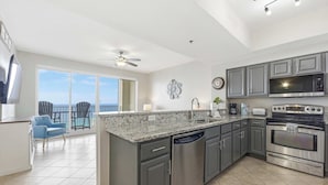 A modern kitchen with a large island, stainless steel appliances, and a view to the outside. - 20th Floor Condo With Stunning View (Miramar Beach)