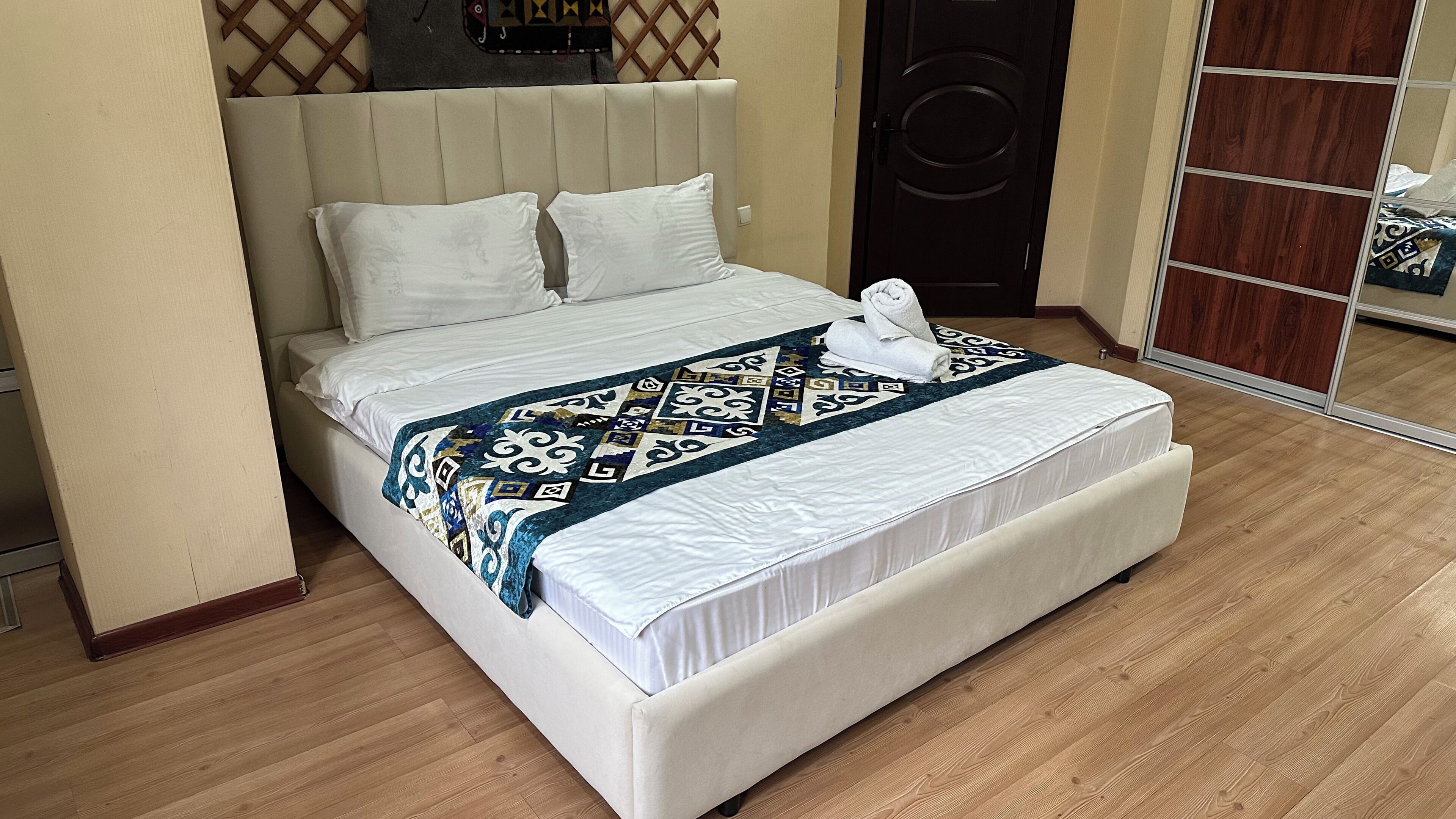 Una cama con colcha estampada, cabecero y suelo de madera.