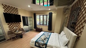 A modern hotel room with a large bed, a desk, a chair, a TV, and a window with curtains. - Gatsby Ortosay (Bishkek)