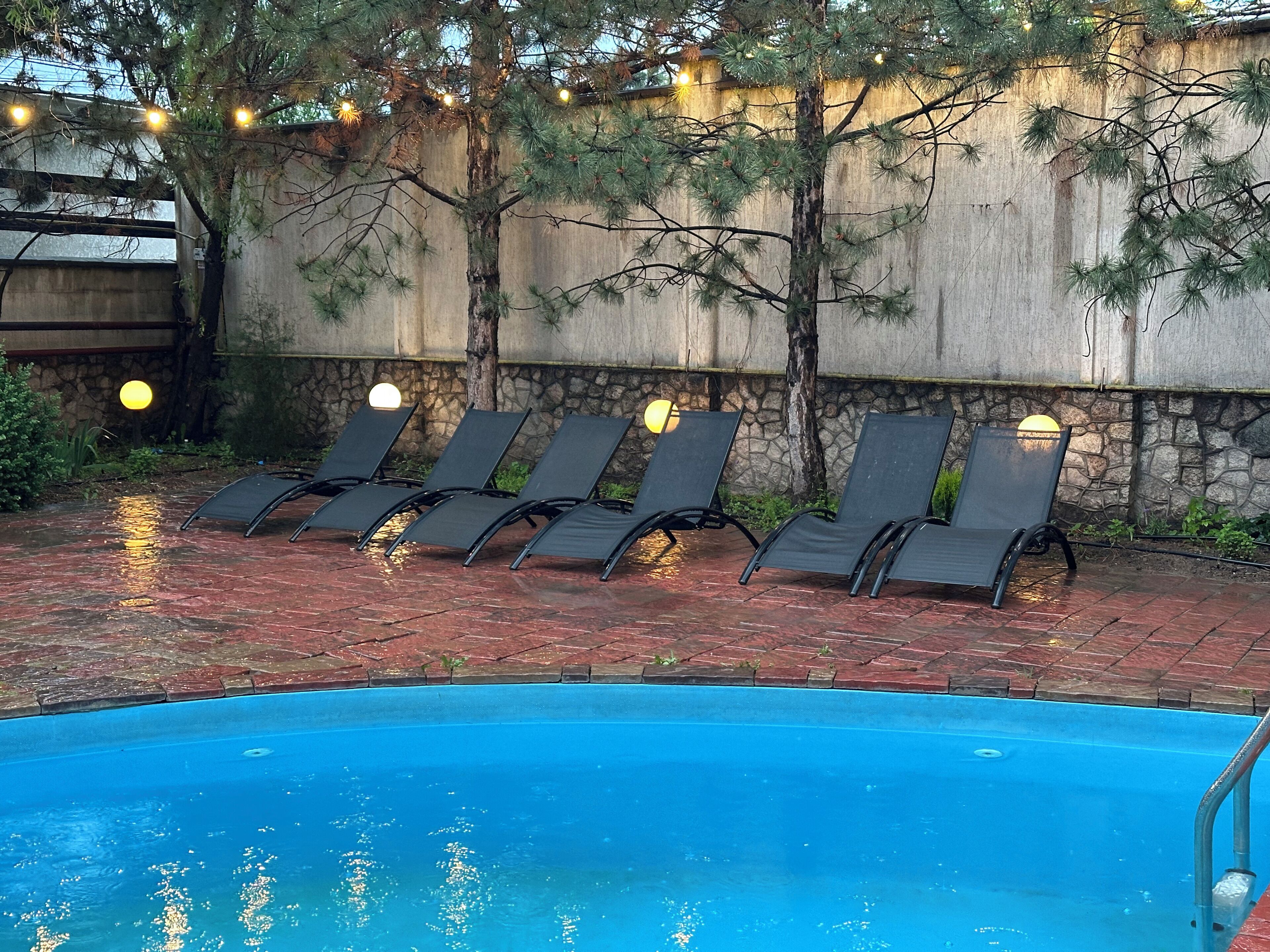 A swimming pool with lounge chairs and string lights.