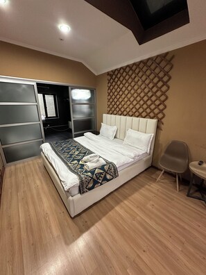 A bedroom with a bed, a wardrobe, a chair, and a wall-mounted TV. - Gatsby Ortosay (Bishkek)