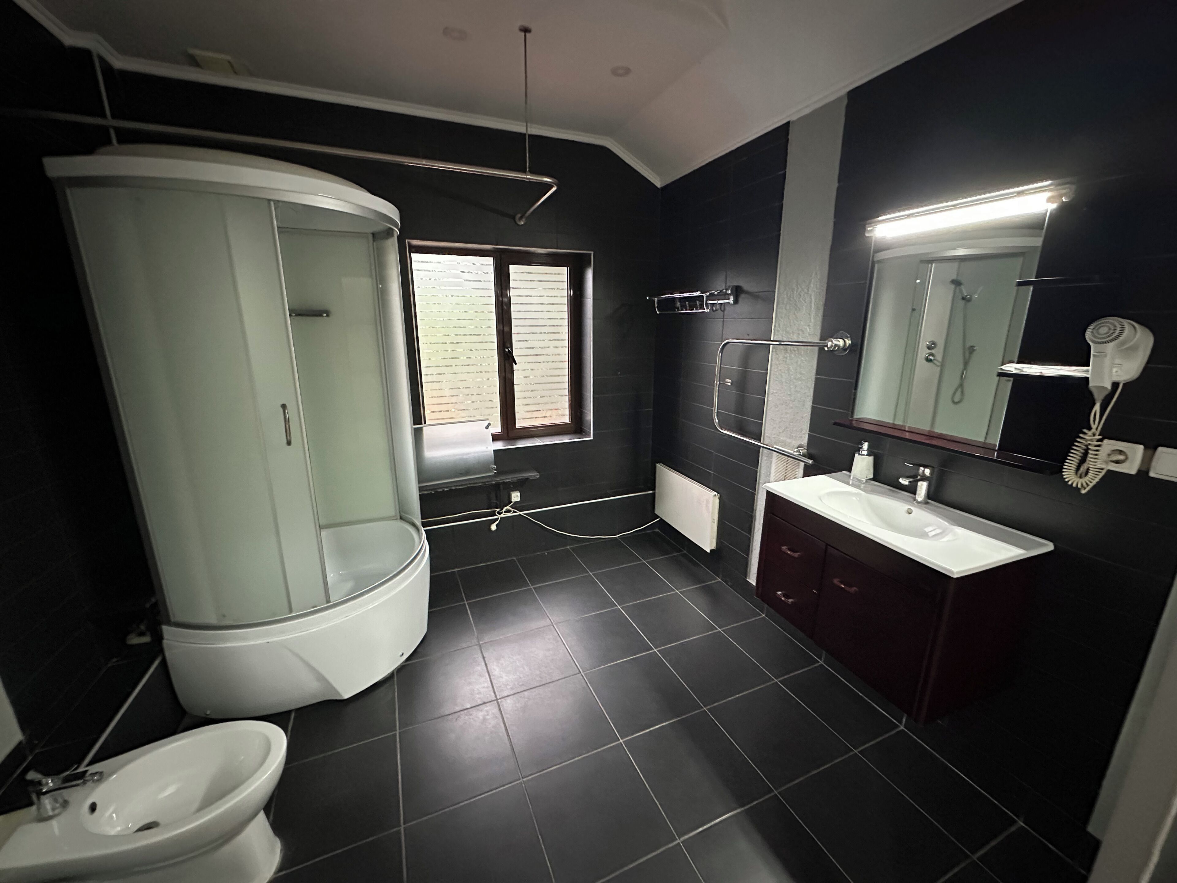 A modern bathroom with a toilet, bidet, sink, and a shower area.
