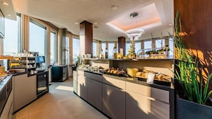 A modern kitchen with a breakfast bar, large windows, and a view of the sea. - aquaTurm Hotel GmbH (Radolfzell am Bodensee)