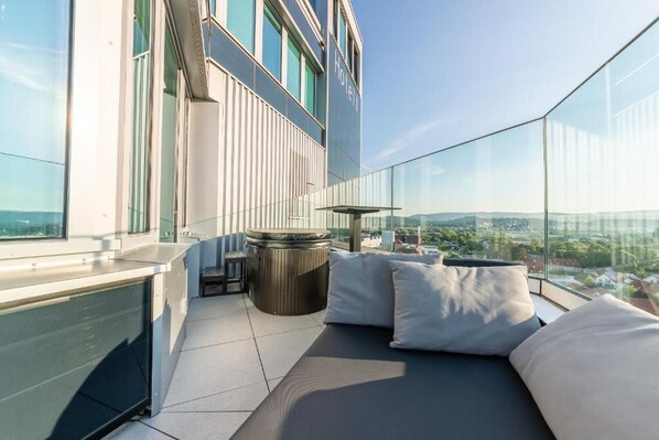 A modern hotel room with a glass balcony, a hot tub, and a city view. - aquaTurm Hotel GmbH (Radolfzell am Bodensee)