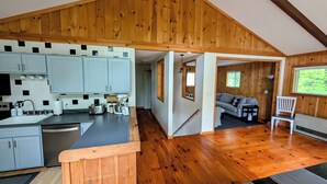 Un'ampia cucina con mobili in legno e una grande isola, una zona giorno accogliente con un divano e una poltrona, e vista sull'esterno da una finestra.