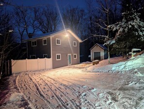 A residential building with a driveway leading to the entrance, surrounded by snow-covered ground and trees.