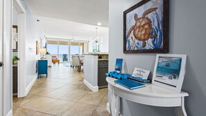 En hotellobby med en receptionsdisk, ett inramat konstverk som föreställer en havssköldpadda och utsikt över köket och matsalen.