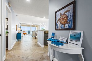 Eine Hotelhalle mit einer Rezeption, einem gerahmten Kunstwerk mit Meeresschildkröte und Blick auf die Küche und den Speisesaal.